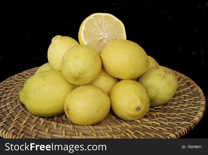 Lemons on the wicker plate in isolated over black