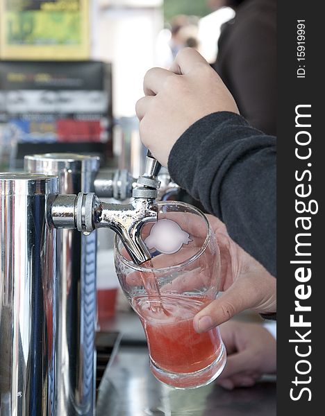 Woman serving a strawberry beer directly from the pump. Woman serving a strawberry beer directly from the pump