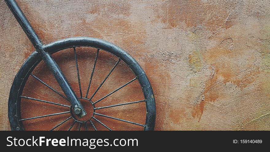 Black iron or steel wheel hanging on brown rough wall with right copy space in vintage tone