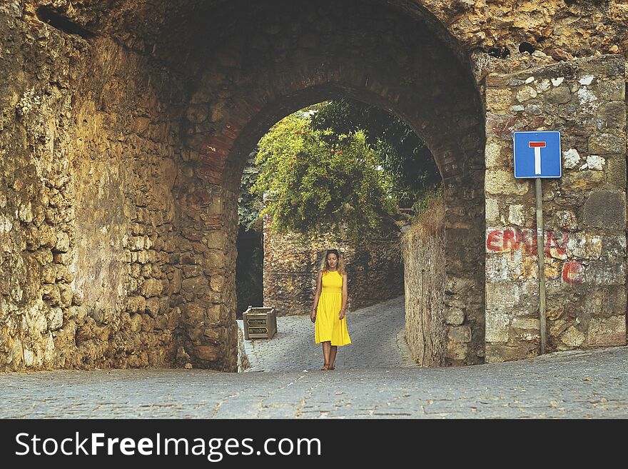 Young beautiful woman in yellow dress close up on the red tower of Alanya.