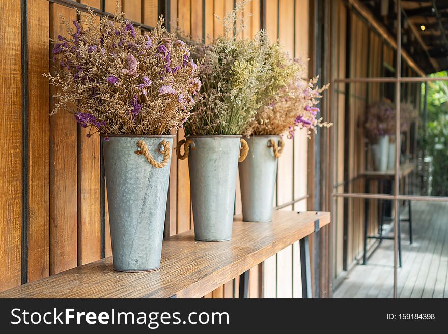 Zinc vase with flowers placed on a wooden table that has black metal legs