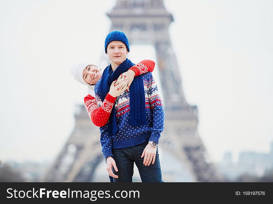 Happy couple near the Eiffel tower on a winter day. Trip to Paris during season holidays