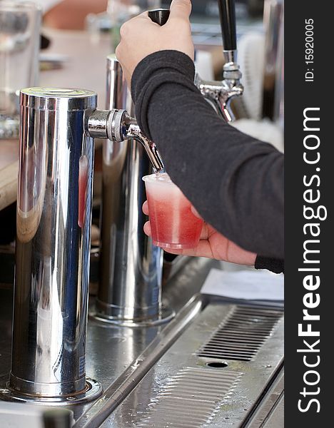 Woman serving a strawberry beer directly from the pump. Woman serving a strawberry beer directly from the pump