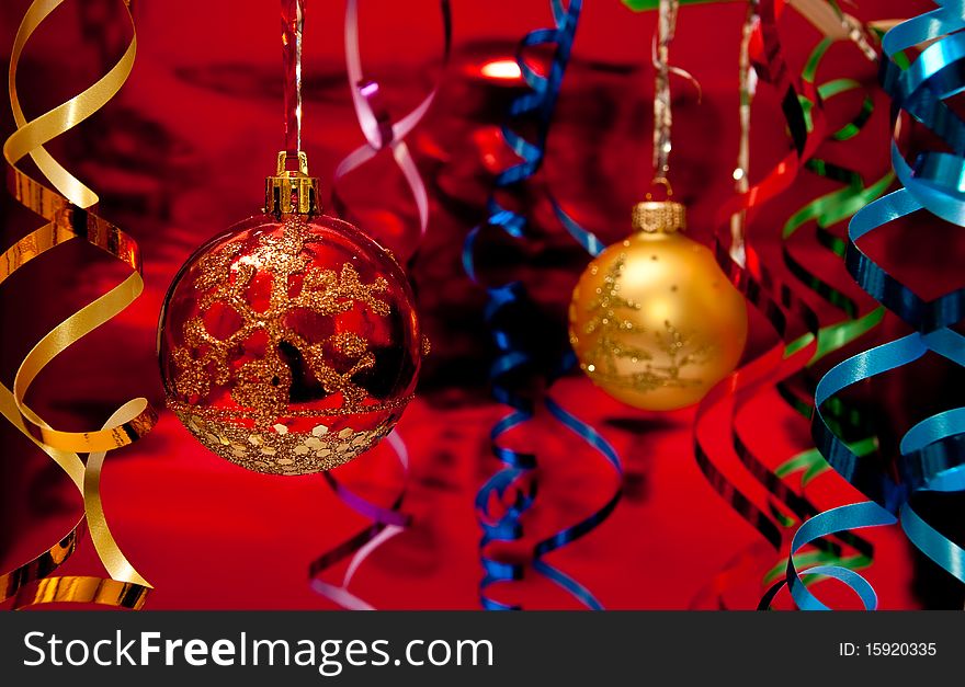 Red christmas ball and colored ribbons. Red background. Red christmas ball and colored ribbons. Red background