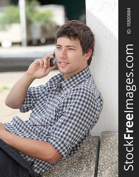 Young man sitting on the ground with mobile phone. Young man sitting on the ground with mobile phone