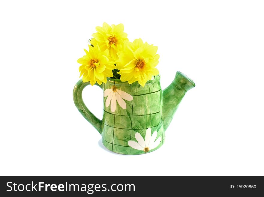 The ceramic green watering can with a bouquet of yellow dahlias is isolated on a white background. The ceramic green watering can with a bouquet of yellow dahlias is isolated on a white background