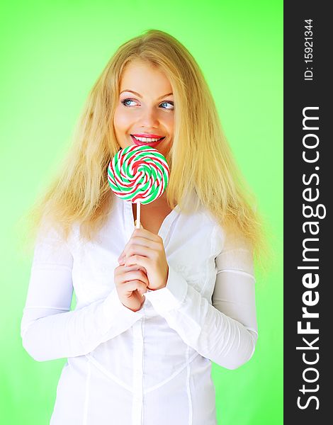 Beautiful girl holding lollipop on a green background