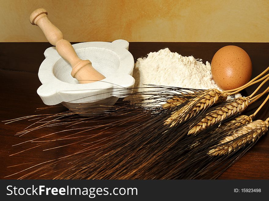 Eggs, flour, wheat ears and mortar on wood table. Eggs, flour, wheat ears and mortar on wood table