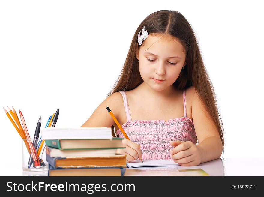 Cute little girl writing something in the copybook with pencils and books near it. Cute little girl writing something in the copybook with pencils and books near it.