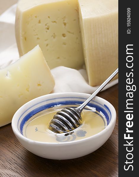 Sheep milk cheese sliced on cutting board with honey