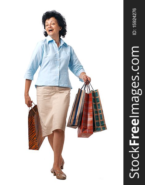 Happy elderly woman walking with shopping bags over white background. Happy elderly woman walking with shopping bags over white background.