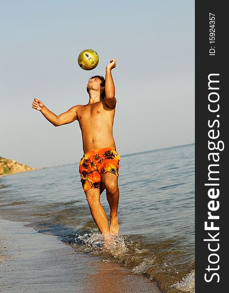 Handsome young man playing football on a sea shore. Handsome young man playing football on a sea shore