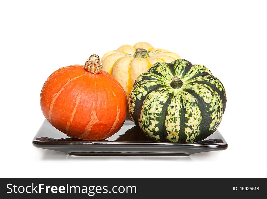Three decorative squashes or gourds on a plate - white background.