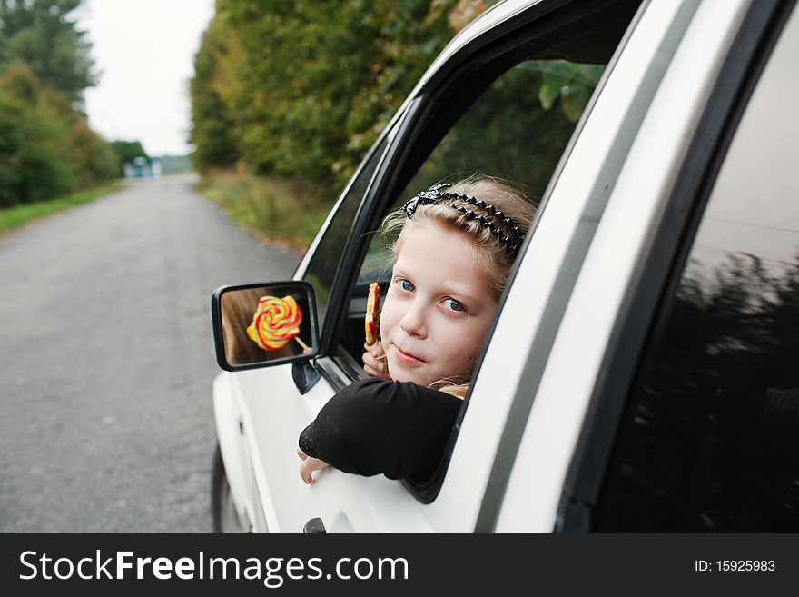 Little girl with a lollipop in his hand sitting in the car. Little girl with a lollipop in his hand sitting in the car