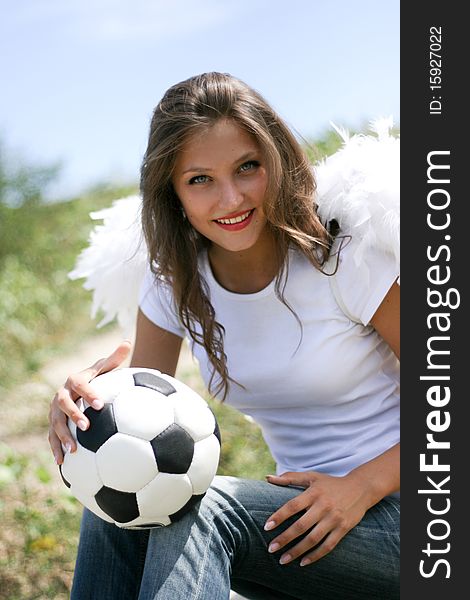 Pretty angel with soccer ball at summer landscape