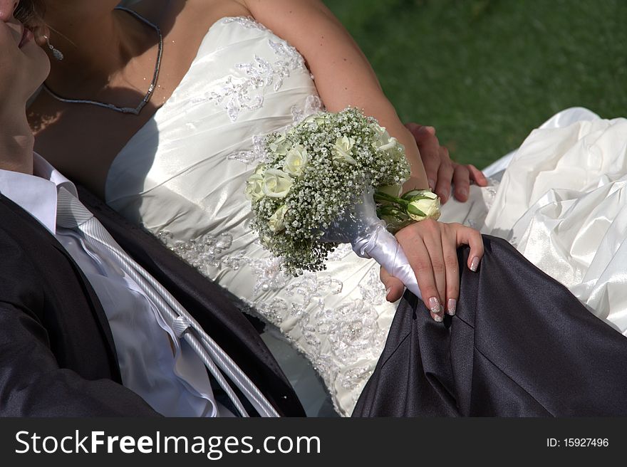 Young couple sit on a grass, fiancee of get on the hip is a wedding bouquet. Young couple sit on a grass, fiancee of get on the hip is a wedding bouquet