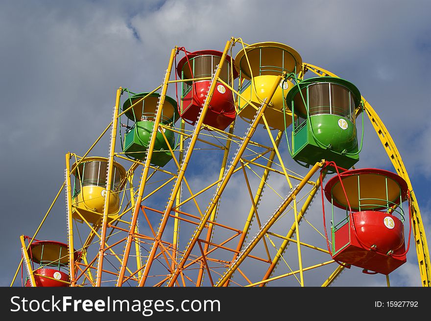 Attraction (Carousel) Ferris wheel on the background of the cloudy sky