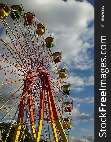 Attraction (Carousel) Ferris wheel on the background of the cloudy sky