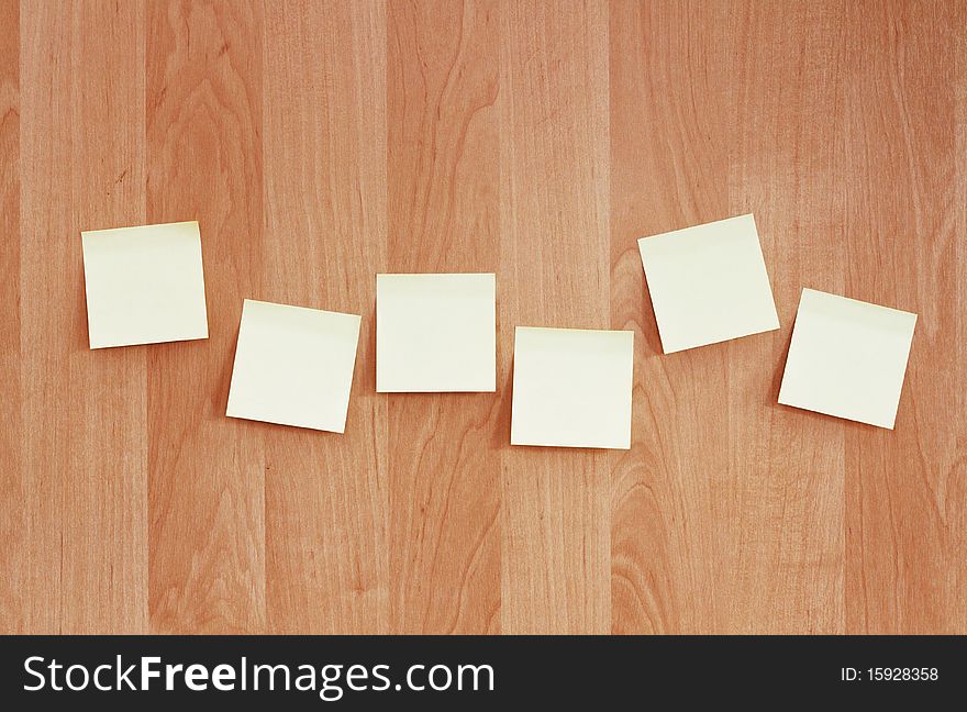 A row of sticky notes pasted on a wooden wall. A row of sticky notes pasted on a wooden wall