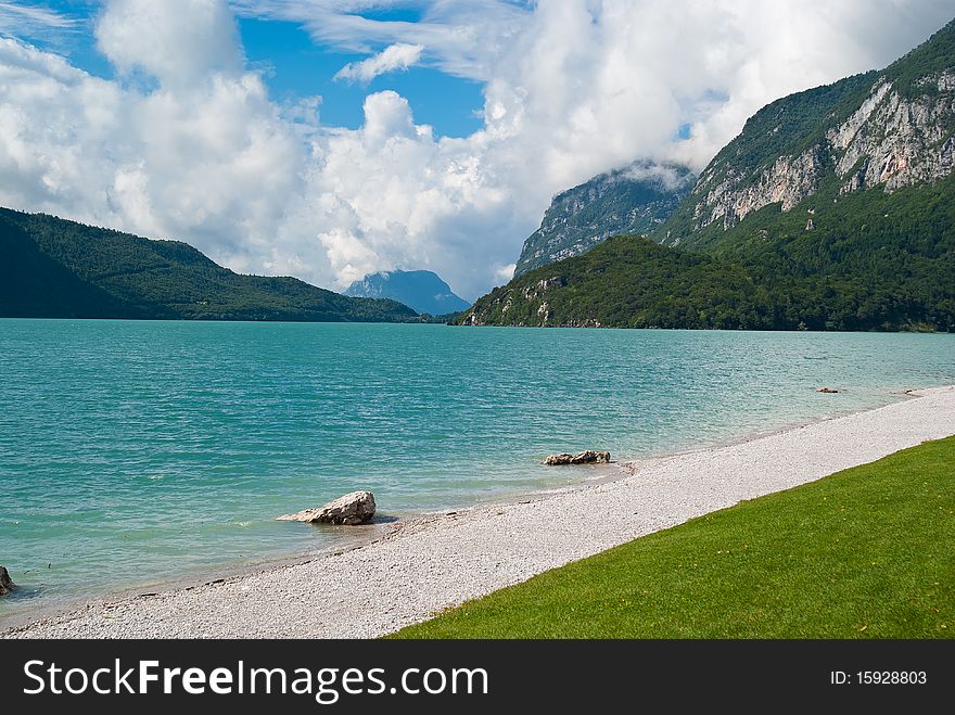 View of mountains reflected on a lake in Trentino in Italy with small waves. View of mountains reflected on a lake in Trentino in Italy with small waves