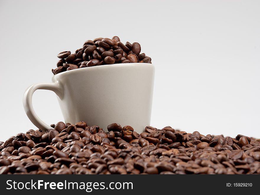 Beige cup of coffee filled of coffee beans. Beige cup of coffee filled of coffee beans.