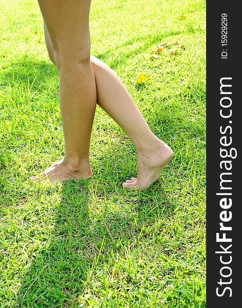 Woman leg stands on the lawn  in daytime