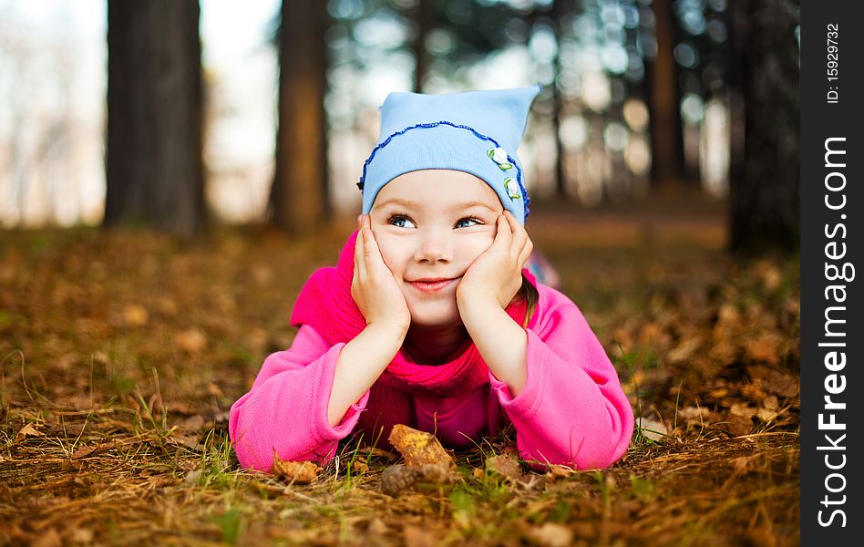 Cute happy little girl on the grass in the autumn park. Cute happy little girl on the grass in the autumn park