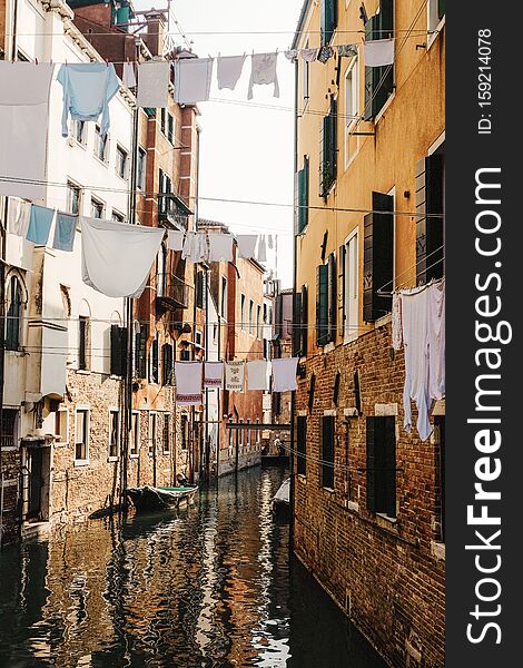 Vertical shot of clothes hanging on a cable between the concrete houses over the river in Venice