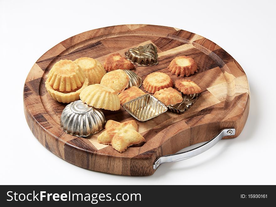Tart shells and baking molds on a cutting board. Tart shells and baking molds on a cutting board