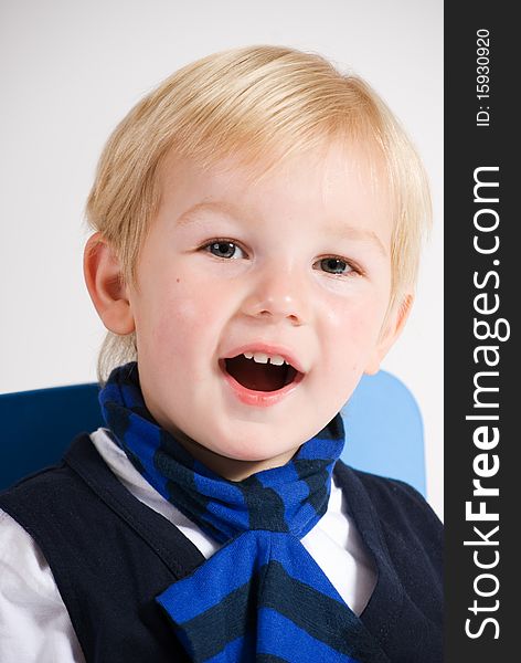 A vertical image of a lovely young blonde boy laughing and smiling