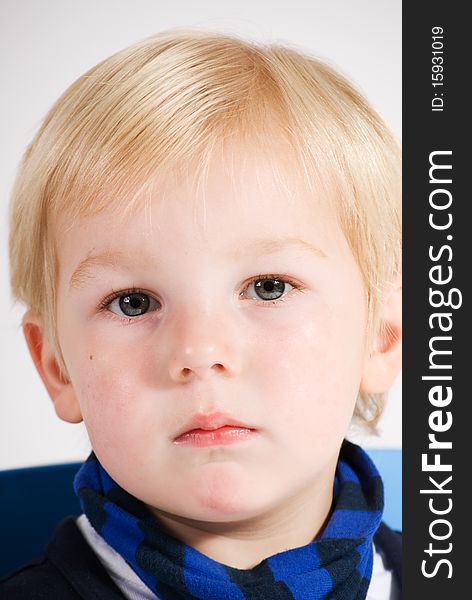 A vertical image of a portrait of a handsome young blonde boy with a serious expression. A vertical image of a portrait of a handsome young blonde boy with a serious expression