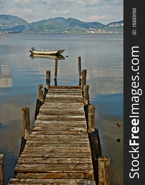 Wooden pier and boat on Lake Massaciuccoli. Lucca Tuscany, Italy
