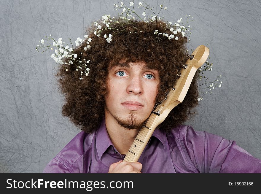 The young guy with curly hair and a guitar in hands. An image of the enamoured romanticist.