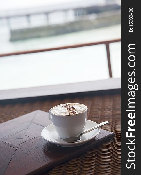 A cup of coffee with ocean at the background