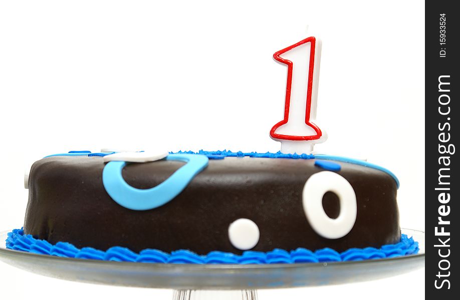 A cake decorated in blue has a number one candle to celebrate that one year mark. A cake decorated in blue has a number one candle to celebrate that one year mark.