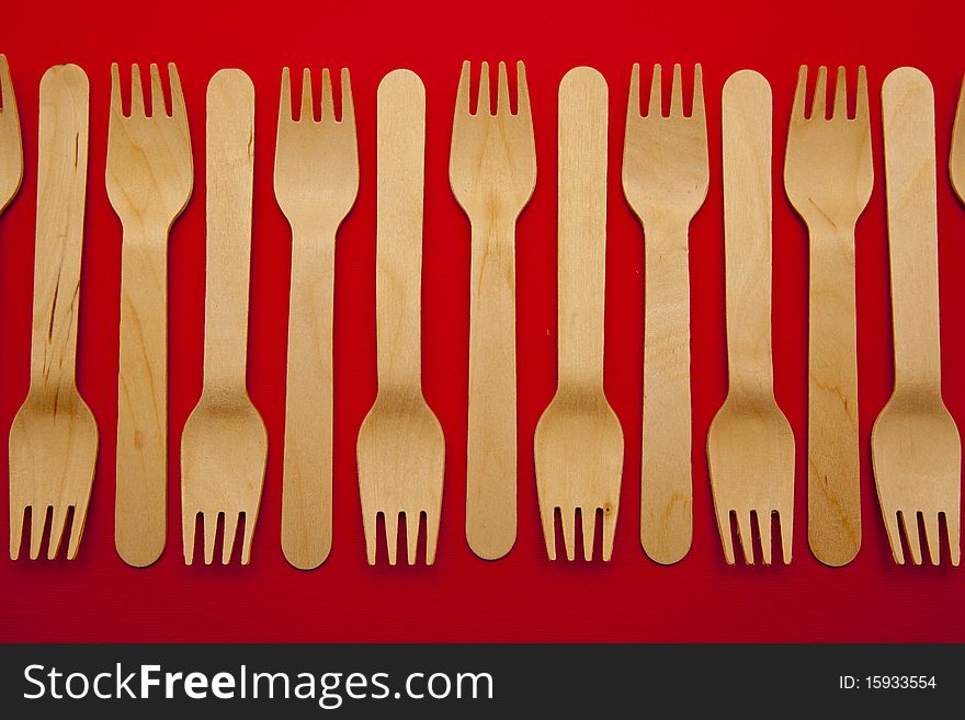 Wooden forks lined up and isolated on a red background