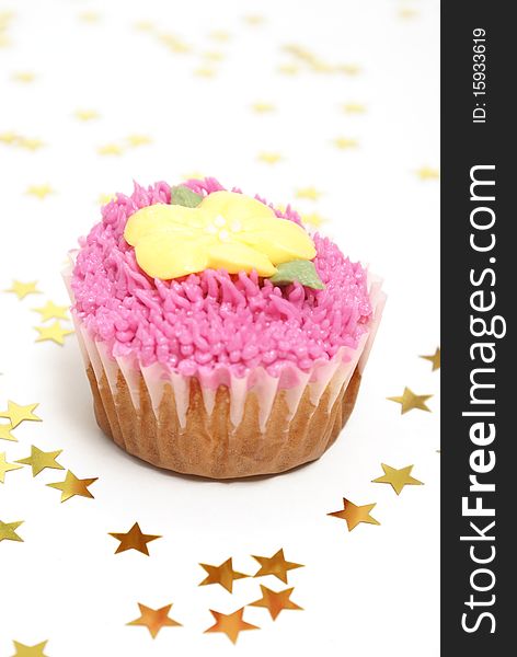 A pink frosted cupcake surrounded by star confetti.