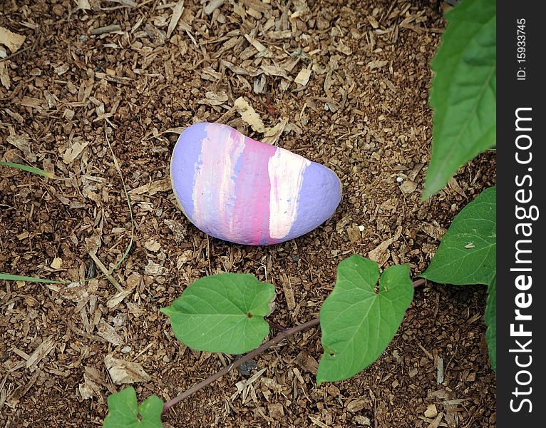 Colorful painted rock in a flower garden. Colorful painted rock in a flower garden.