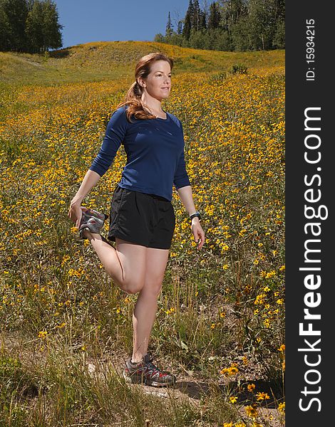 Young woman stretching her quadriceps on a trail. Young woman stretching her quadriceps on a trail.