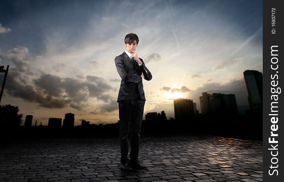 Businessman reflecting with sunset over a city on the background. Businessman reflecting with sunset over a city on the background