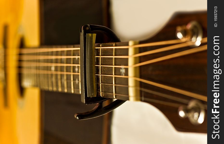 The capo on an acoustic guitar fingerboard. The capo on an acoustic guitar fingerboard.