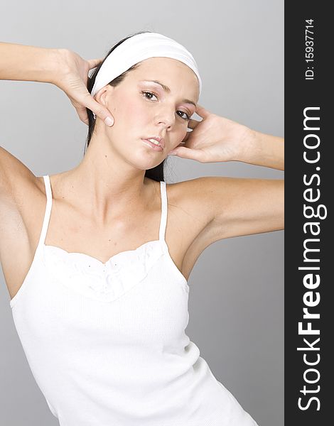 Healthy woman in white top by grey background wearing white band on head