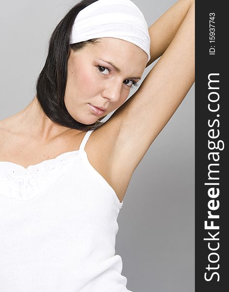 Healthy woman in white top by grey background wearing white band on head