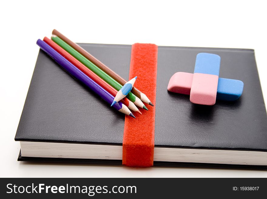 Colored pencils with eraser on book. Colored pencils with eraser on book