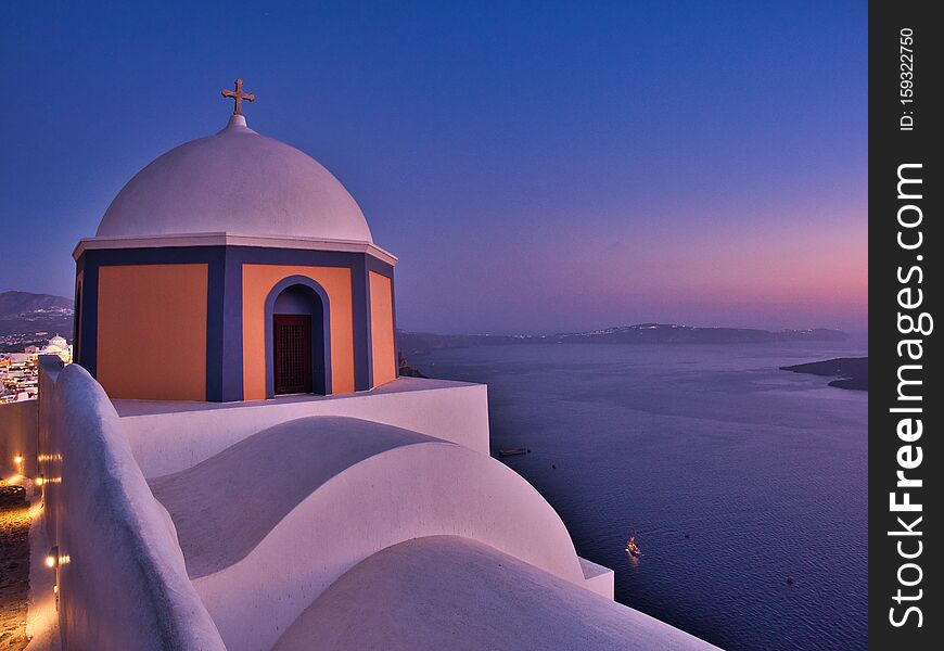 Picturesque view of traditional domed cathedral above tranquil sea at sunset in Fira Santorini Greece. Picturesque view of traditional domed cathedral above tranquil sea at sunset in Fira Santorini Greece