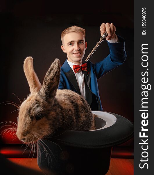 A young guy magician illusionist holding a hat with a rabbit