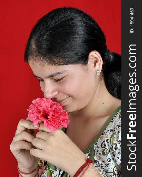 Beautiful girl smelling red flower