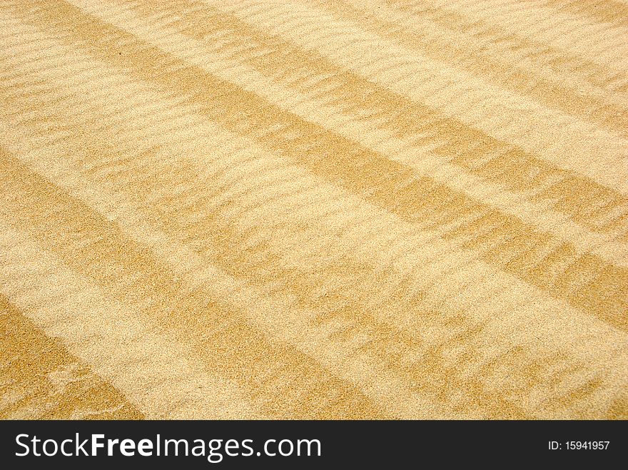 Waved beach sand background with old weathered vehicle tracks. Diagonal orientation. Waved beach sand background with old weathered vehicle tracks. Diagonal orientation