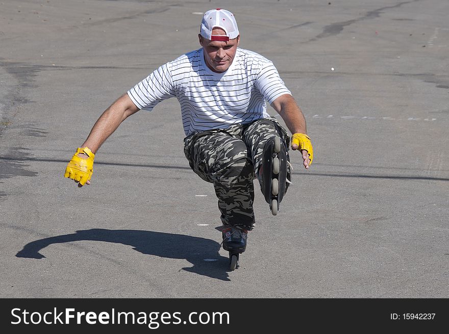 The man goes for a drive on roller skates in a sunny day.