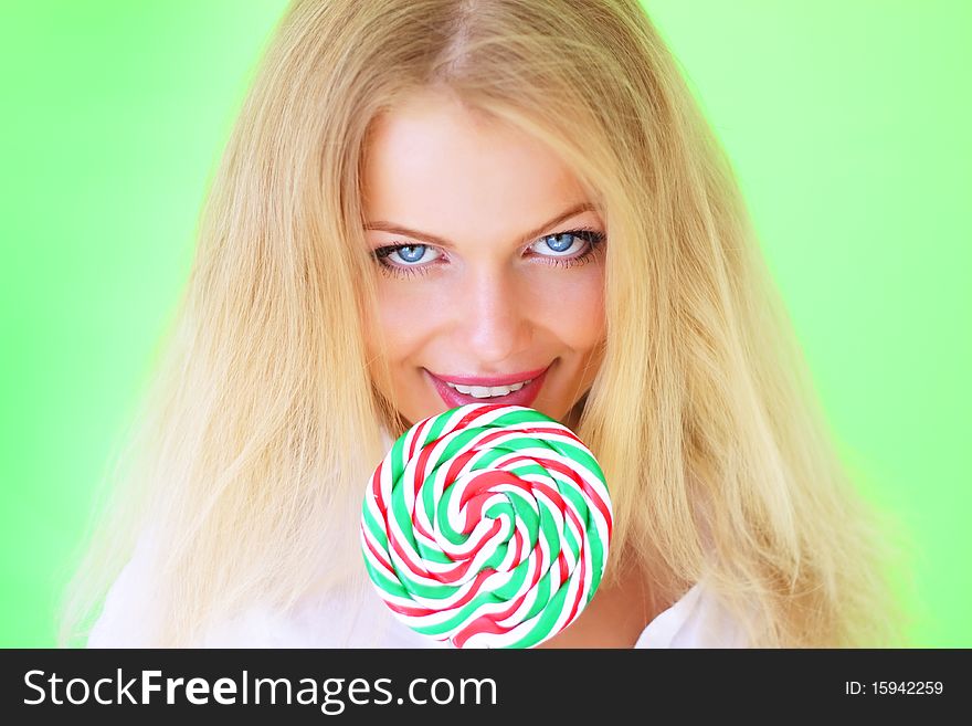 Beautiful girl holding lollipop on a light background